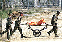 A prisoner at Guantanamo Bay being carted from one area to another like luggage.
