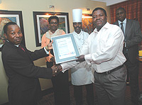 Mugo W. Maringa (L), Kigali Serena Hotel Country Manager receiving a certificate from Ronald Matsiera, the SGS representative.