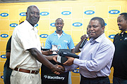 WINNERu2019S SMILE: Joseph Semwaga receives the April mug plus a BlackBerry handset from the outgoing CEO of MTN Rwanda Themba Khumalo (Photo / G. Barya)