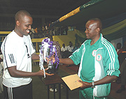 Minister Joseph Habineza hands the Volleyball trophy to APR team captain.