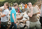UK Conservative Party delegation members carry stones for the construction of a drainage system in Kicukiro. (Photo/J .Mbanda)