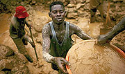 Men sift through buckets of dirt while looking for gold at an abandoned industrial mine in Mongbwalu, Congo