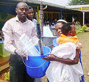 Jean Claude Ndagijimana, the Director of Rwamagana district hospital handing over an assortment of  rewards to a mother beneficiary.Photo S Rwembeho