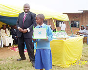 Microsoft Corporation representative David Ochanda gives out a Laptop to one of the best exam performing girls at Inyange Primary School. (Photo: A. Gahene)
