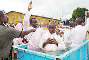 Thu00e9ophile Nkundiye with right hand raised, the accused ADEPR Pastor makes a baptismal prayer in Gitarama prison recently. (Photo: D. Sabiiti)