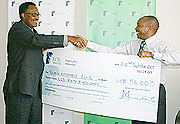 ALL SMILES: KCB Rwanda Managing Director Maurice Toroitich (R) hands over the cheque to RAC boss Dismas Kayibanda yesterday. (Photo / F. Goodman)