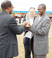 NURC boss, Jean Baptiste Habyarimana presents the award to the World Vision Country Director, Edward Kalisa as Africa Chief Operating Officer, Tim Andrews looks on.