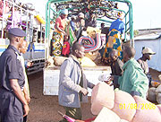 A policeman oversees refugees offloading their luggage at a transit camp in Byumba.