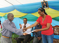 Hon. Agnes Kalibata (R) handsover a cheque to the Head of the Cooperatives that own shares in Gikonko rice factory.