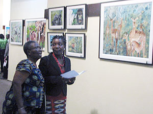 Sandra Idossou (wearing a red necklace), explains to one of the guest the paintings.