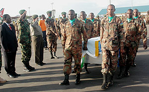 Soldiers carrying caskets bearing the remains of the fallen soldiers yesterday at Kigali International Airport (Photo John Mbnada)