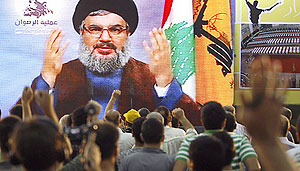 Lebanese Hizballah supporters listen to a televised speech by the partyu2019s chief Hassan Nasrallah during a celebration marking the first anniversary of the prisoners swap with Israel