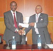 Dr Richard Sezibera receives the cheque from Ambassador Gladstone Dumisani Gwadiso.