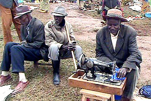 Jonas Rwabukwisi working on his sewing machine in company of fellow old men (photo S Nkurunziza)