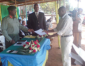 The Minister of Defence Gen.Marcel Gatsinzi and Jean Sayinzoga hand over acertificate to one of the discharged officers.