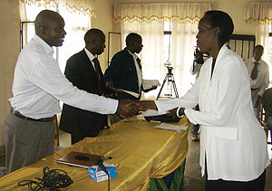 Anasthase Barinda hands over a certificate of participation to Venansia Kabazayirwa.