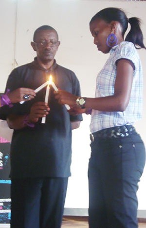 Rwandan High Commissioner in Uganda, Frank Mugambage lights candle to Miss E.A, Cynthia Akazuba.