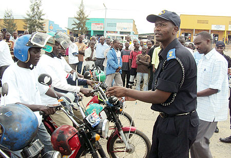Supt. Du00e9siru00e9 Tuyizere placing a sticker on motorists in Gitarama. (Photo: D. Sabiiti)