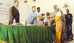 Muhamoud Abudalazim handing over an envelope and scholastic materials to one of the beneficiaries yesterday. (Photo / F. Ndoli)