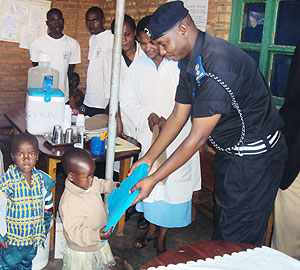 Supt. Alex Rutabayiro distributes mosquito nets to children. (Photo: S. Nkurunziza)