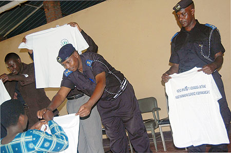 Supt. Alex Rutabayiro, the Karongi District Police commander (C) leads other officers in distribution of t-shirts as part of the 10th anniversary. 