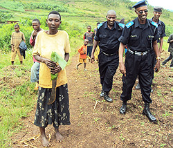 Marie Nyiramungu with the machete she used to kill her children and husband, as the police escorts her from her hide out  to a waiting Police vehicle.