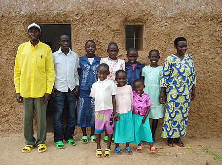 Valens Ntakirutimana (extreme left) stands infront of his house with the family. (Photo by Sarah Boseley, The Guardian UK)