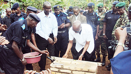 Minister Fazil Harerimana (R) and Empraim Kabaija lay a foundation stone at the first house built as Police officers look on. (Photo; S. Rwembeho)