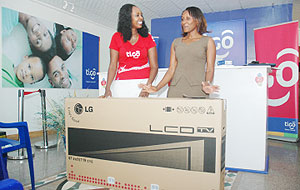 A delighted Uwera Gloriose (Right) flanked by Tigou2019s marketing manager Nina Claudia Ndabaneza shortly after receiving her LG flat screen at Tigo Tower yesterday. (Photo F. Goodman)