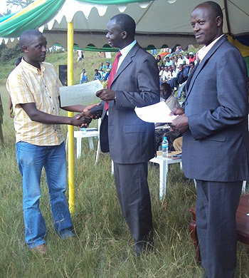 The Minister of Environment and Natural Resources, Stanislas Kamanzi handing over a land registration certificate to one of the residents (Photo; F. Ndoli)