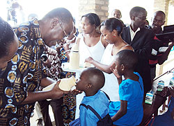 Prime Minister Bernard Makuza feeds a child with milk in Musambira sector yesterday . (Photo; D. Sabiiti)