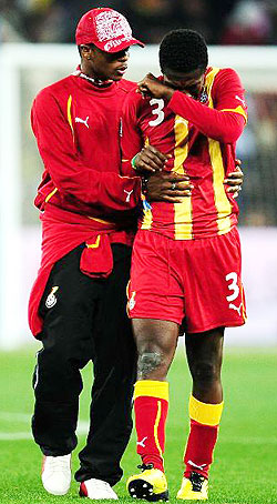 Asamoah Gyan is consoled by a teammate after he missed the penalty that wouldu2019ve given Ghana a win in normal time. (Net photo)
