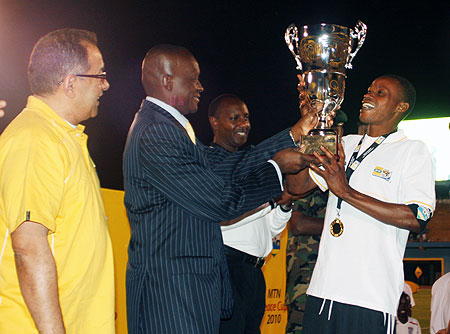 Sports Minister Joseph Habineza gives the MTN Peace Cup title to APR skipper Patrick Mafisango as MTN CEO Mikkawi Khaled looks on yesterday at Amahoro stadium. Photo;E.Niyonshuti