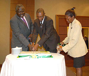 Frank Mugambage and Ugandau2019s State Minister for International Cooperation, Okello Oryem cut a cake as part of celebrations in Kampala. (Photo; G. Muramira)
