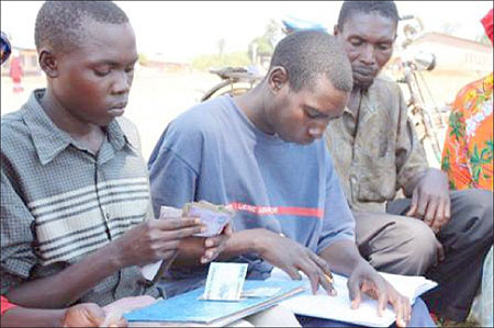 Albert Maniraguha (left) receives and counts money and monthly contributions from members of Terimbere SILC group.
