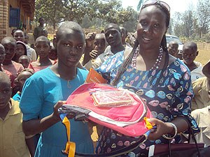 Judith Murara Murekeyisoni hands over a prize to Betty Nyirarenzaho,one of the best female pupils in science at Byiza Primary School. (Photo: J. Bucyensenge)