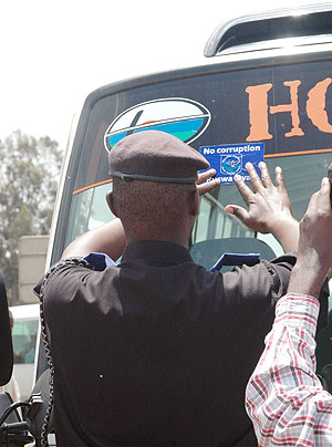 A Police officer puts a No Corruption sticker on a commuter omnibus. Reports have indicated  decreasing corruption cases in the country. (File photo)