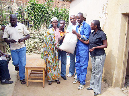 RECO-RWASCO staff handing over a bag of rice to Mukashema (C) on Friday ( Photo by A.Gahene)