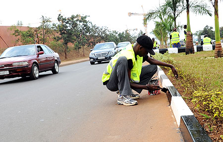 GIVING THE ROADS A FACELIFT; Workers painting Kigali City street pavements ahead of the swearing in ceremony slated for Monday (Photo: J. Mbanda)