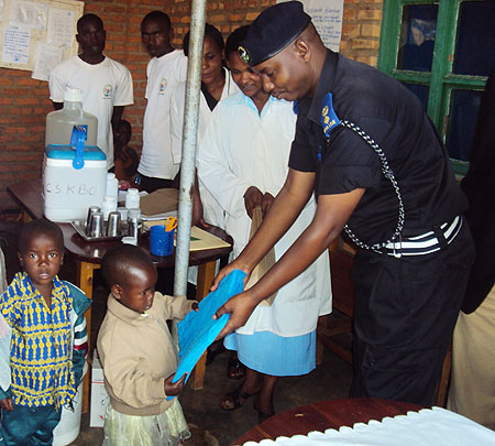A police officer Supt. Alex Rutabayiro distributes mosquito nets to children in western Rwanda in April this year. File photo