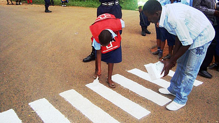 One of the students painting a zebra crossing along Nyagatare-Ryabega road. (Photo.D.Ngabonziza)
