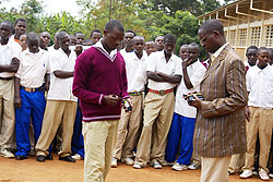 Hon. Harebamungu (R) confiscating studentsu2019 cell phones in Zaza (Photo; S. Rwembeho)