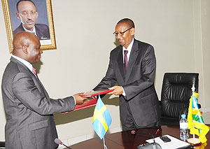 Finance Minister John Rwangombwa and Head of SIDA Richard Bomboma exchange documents after signing. (Photo J Mbanda)