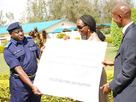 Commisoner General Of Police Emmanuel Gasana hands over a dummy cheque to the Minister of Agriculture, in support of suport One Cow per Family programme Photo T.Kisambira)