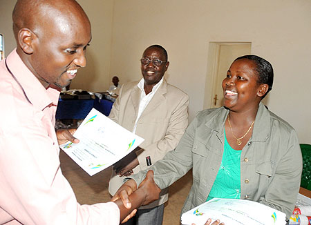 Gisozi Sector Executive Secretary, Patrice Murekatete, awarding a certificate to an election volunteer (Photo T.Kisambira)