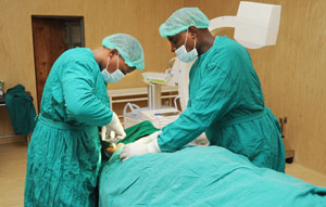 Dr. King Kayondo (L) removing a fragment from a Patientu2019s leg at Kanombe Hospital on Monday. (Photo J Mbanda)
