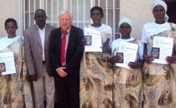 Mike Hughes and Mayor Louis Rwagaju  with the women after receiving their travel documents. (Photo S. Rwembeho)