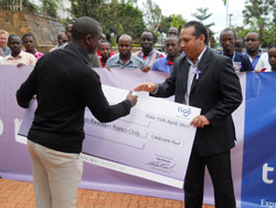 TIGOu2019s Head of Sales and Customer Care, Diego Camberos hands over a cheque of Rwf1 million to the Kigali Memorial Centre administrator (courtesy photo).