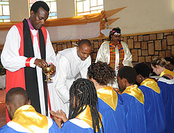 Kigali Diocese, Bishop Louis Muvunyi of St.Etienne (L) administers Holy communion to members of the churchu2019s choir during the Easter service, yesterday.(Photo J Mbanda).
