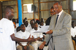 Demobilisation commission chairman, Jean Sayinzoga hands a certificate to ex-combatants after completing a course during a past event (File Photo)
